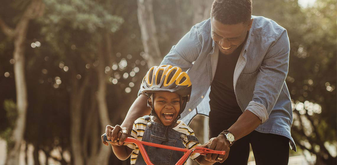 Dad teaching his son to ride a bike.