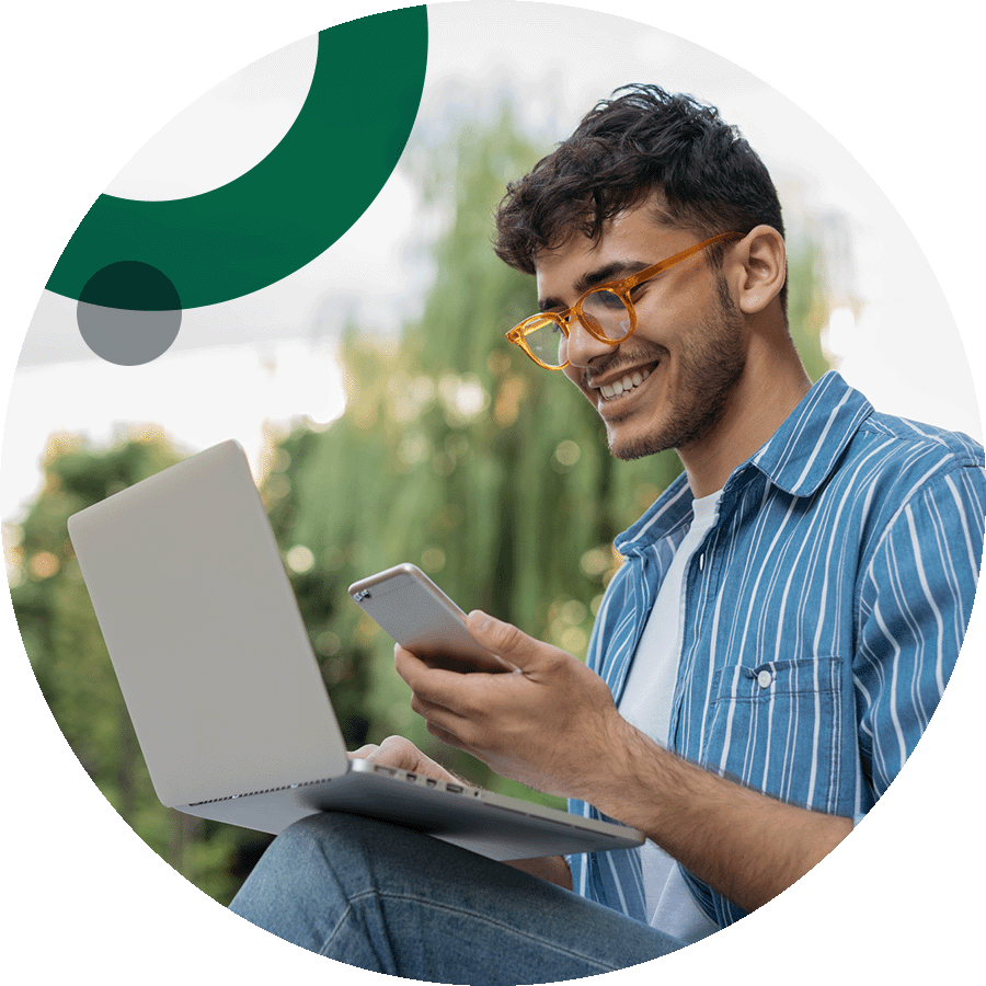 Happy man using laptop and mobile outside