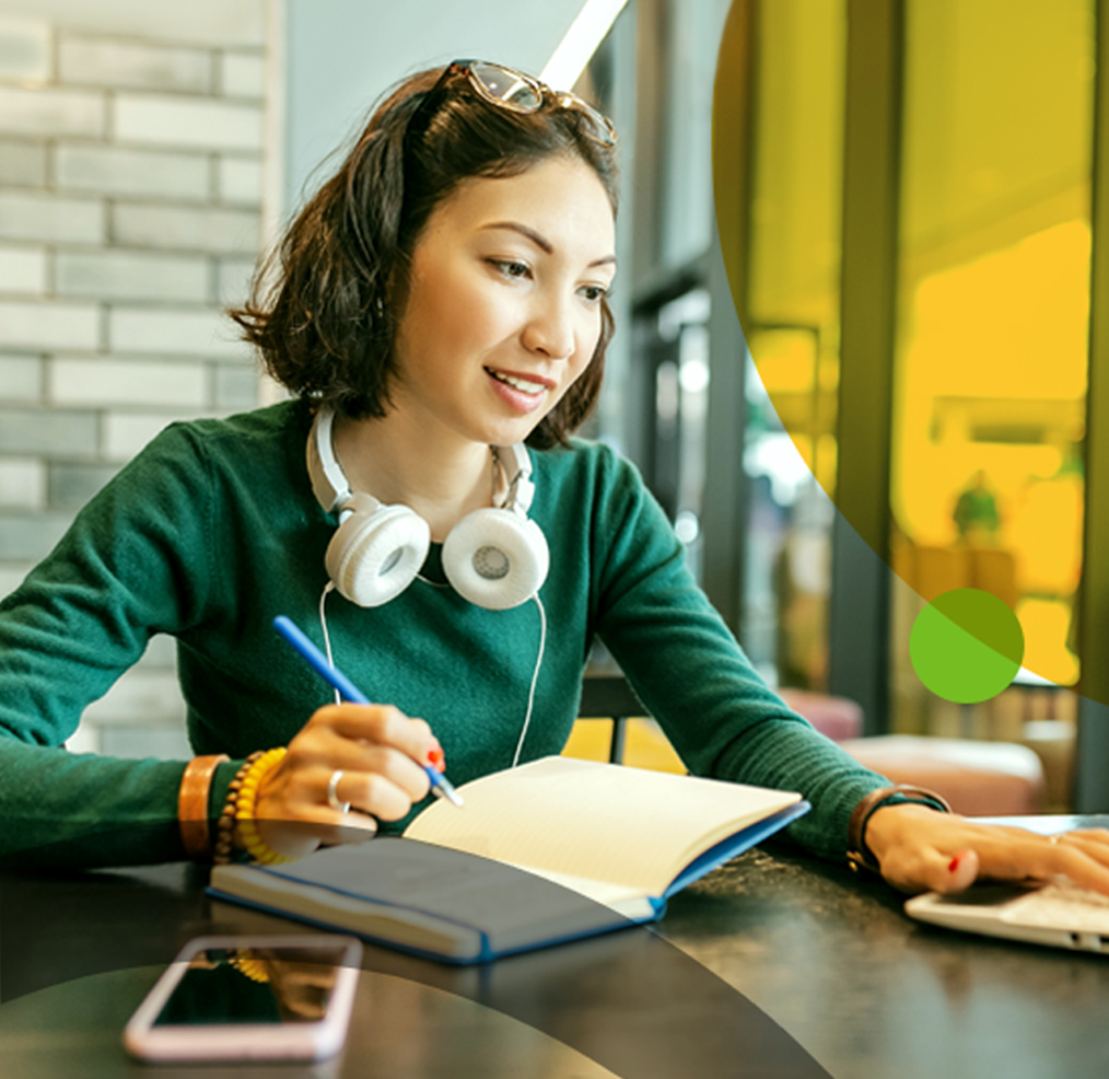 Student taking notes and using laptop