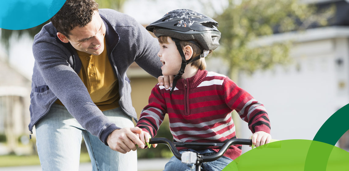 Father teaching son how to ride a bike